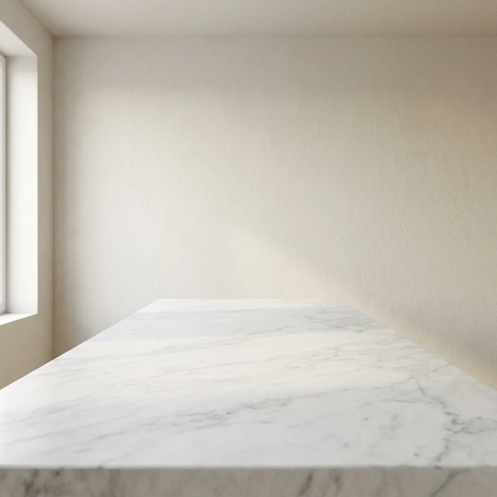 An empty white marble counter in front of a warm plaster wall with a window on the left